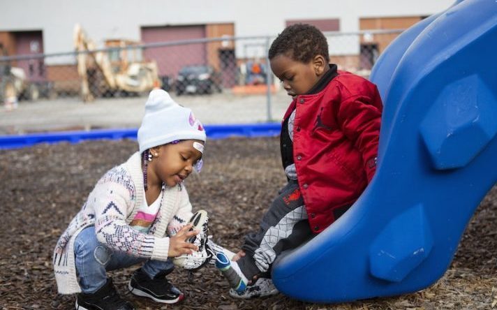 child helps a friend with his shoe