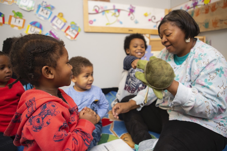 teacher playing with a turtle puppet with students