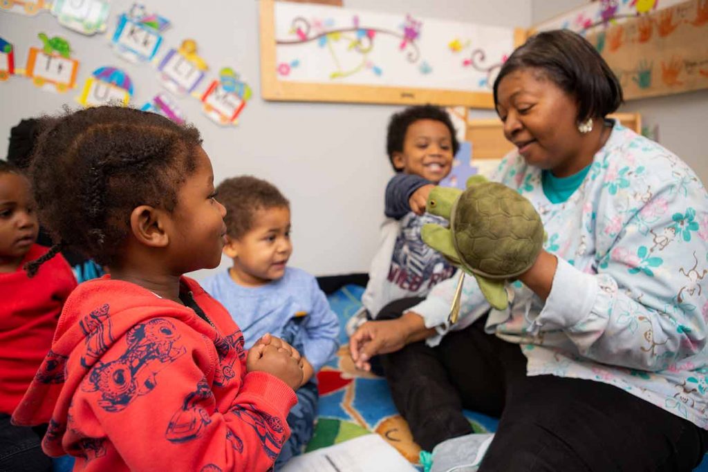 Teacher playing with a turtle puppet in small group