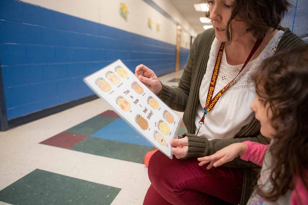 child and teacher looking at emotions chart