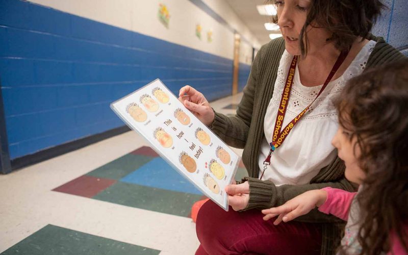 child and teacher looking at emotions chart