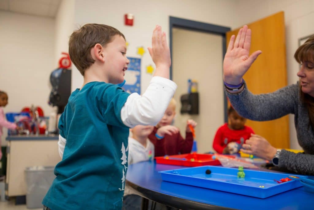 Child and teacher high five and smile