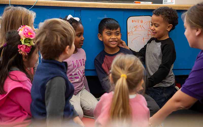 A group of young children in circle time greeting each other